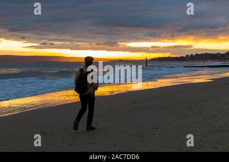 Bournemouth, Dorset UK. 1. Dezember 2019. UK Wetter: atemberaubende Sonnenuntergang am Strand von Bournemouth am Ende einer bitter kalt trockenen sonnigen Wintertag. Person zu Fuß entlang der Küste bei Sonnenuntergang. Credit: Carolyn Jenkins/Alamy leben Nachrichten Stockfoto