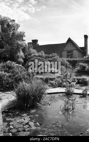 Mit einer verkabelten Vorderseite des Great Dixter Manor, das um 1450 erbaut wurde und über einen Teil von Christopher Lloyd's Sunken Garden blicken kann. Altes Schwarzweiß-Filmfoto, ca. 1980 Stockfoto