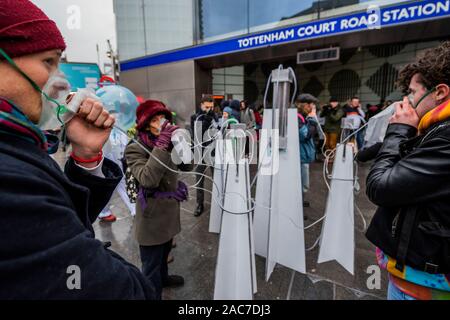 London, Großbritannien. 1. Dez 2019. Aussterben Rebellion Theatrics bringen Theater (zeigt, wie man in der Zukunft zu atmen saubere Luft atmen können Hubs bezahlen) und Krise Carollers zu Tottenham Court Road, bevor Sie marschieren die Oxford Street in Verschmutzung Masken. Beginn der Ausrottung Rebellion 12 Tagen der Krise das Klima und Ökologische Not ist ganz oben auf der Tagesordnung dieser Wahlen zu gewährleisten. Credit: Guy Bell/Alamy leben Nachrichten Stockfoto