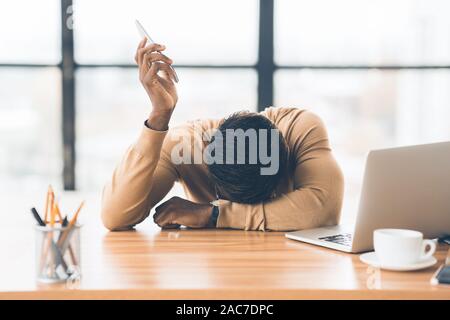 Erschöpft afrikanische amerikanische Geschäftsmann mit Mobiltelefon Stockfoto