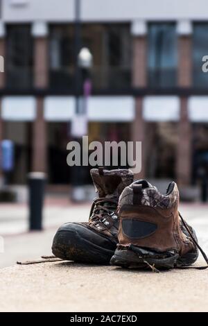 Ein paar alte abgenutzte Schuhe Schuhe sitzen auf eine Betonwand. Stockfoto