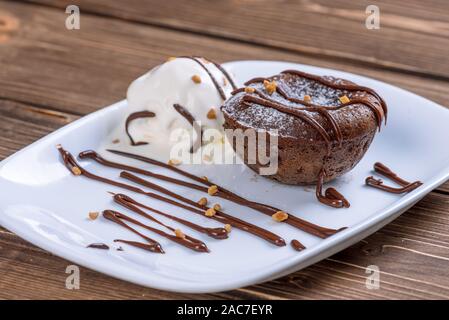 Konzept: Speisekarten, gesundes Essen, hausgemachte, Feinschmecker, Völlerei. Weißen Teller mit Schokolade Fondant und Eis auf einem chaotisch Vintage Holz b Stockfoto