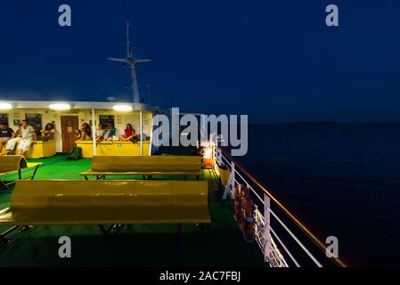 Die Passagiere sitzen auf Reihen von gelben Kunststoff sitze auf dem oberen Deck der Fähre im Zadar Archipels nach Sonnenuntergang in der Dämmerung, Kroatien Stockfoto