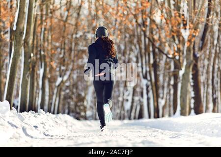 Ein Mädchen läuft durch den Park im Winter Stockfoto