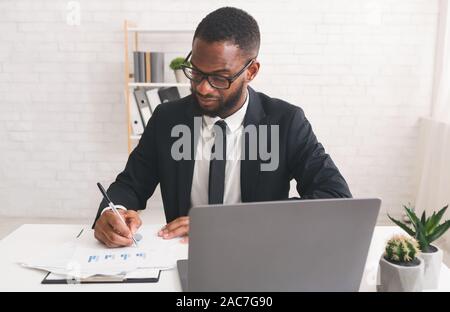 Ernsthafte junge Manager arbeiten mit Dokumenten in seinem Büro Stockfoto