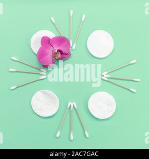 Rahmen mit Wattestäbchen und Auflagen auf einer Münze Hintergrund. Orchid Flower. Umweltfreundlich. Konzept Kosmetik Stockfoto