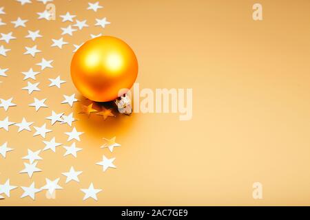 Urlaub Hintergrund mit kleinen silbernen Sterne mit Christmas Ball auf goldenem Hintergrund. Festliche Kulisse. Stockfoto