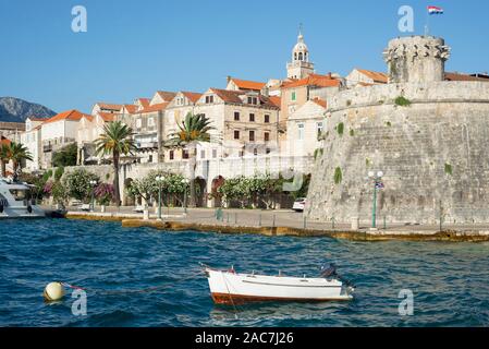 Boot im Hafen vor der steinernen Fassaden der Altstadt von Korčula in der Abendsonne, Insel Korcula, Dalmatien, Kroatien Stockfoto