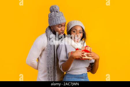 Happy afro winter girl Holding Weihnachtsgeschenke, Freund hinter einem Aufenthalt Stockfoto