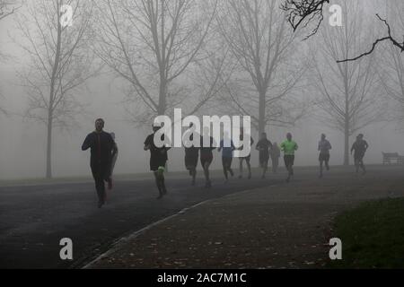 Athleten jog inmitten dichter Nebel in Finsbury Park, nördlich von London. Stockfoto