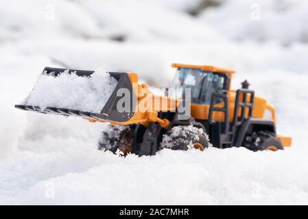 Ein Spielzeug Traktor Reinigung Straße von einem Schnee Konzept. Stockfoto