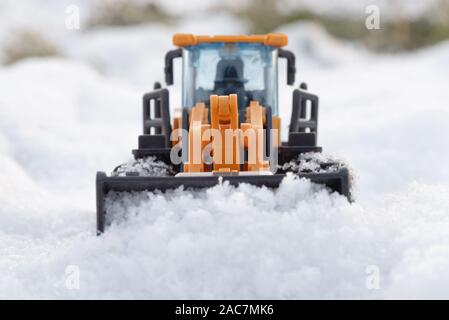 Ein Spielzeug Traktor Reinigung Straße von einem Schnee Konzept. Stockfoto