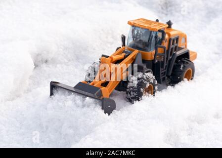 Ein Spielzeug Traktor Reinigung Straße von einem Schnee Konzept. Stockfoto