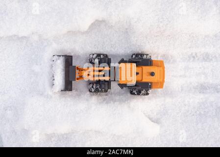 Ein Spielzeug Traktor Reinigung Straße von einem Schnee Konzept. Stockfoto