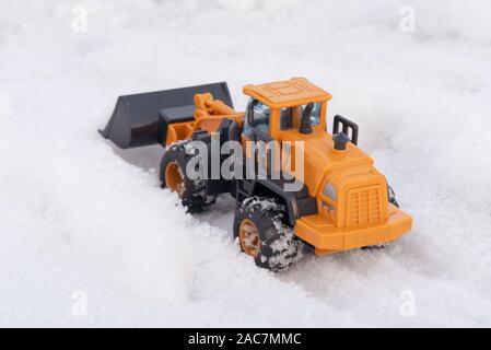 Ein Spielzeug Traktor Reinigung Straße von einem Schnee Konzept. Stockfoto