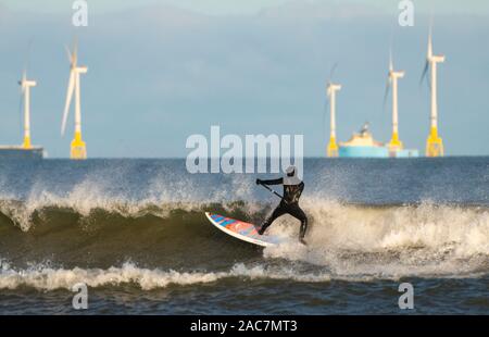 Aberdeen, Schottland, Großbritannien. 1. Dezember 2019. Surfer nutzten heller Sonnenschein und günstige Winde gute Wellen entlang der Strand in Aberdeen. In der Ferne sind Windenergieanlagen der Europäischen Offshore-windenergie Deployment Center Wind Farm. Iain Masterton/Alamy Leben Nachrichten. Stockfoto