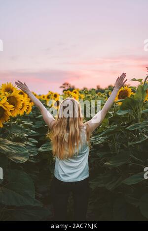 Glückliche Frau erhobenen Händen in Sonnenblumen Feld Harmonie mit der Natur Reisen gesunder Lebensstil im Freien Ferien allein Stockfoto