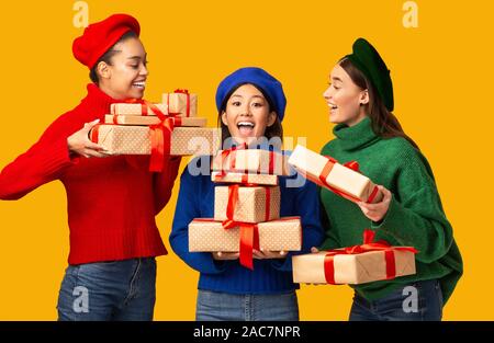 Diverse Mädchen gratulieren Freund gibt ihr präsentiert Über gelben Hintergrund Stockfoto