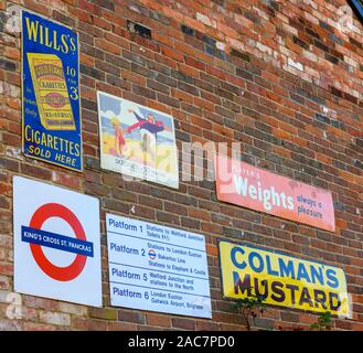 Vintage metall Werbe- und Hinweisschilder an der Seite eines privaten Hauses, Newbury Street, Whitchurch, Hampshire, England, Großbritannien Stockfoto