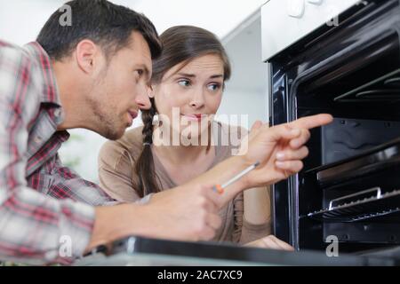 Frau und Mann Kontrolle einen Backofen problem Stockfoto