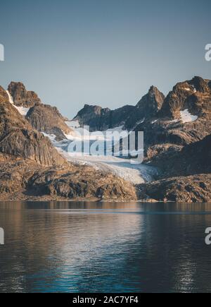 Arktische Landschaft im Sommer mit hohen Bergen und Eisberge auf dem Meer in Ofjords, Scoresby-sund, Ostgrönland. Foto in Grönland. Stockfoto