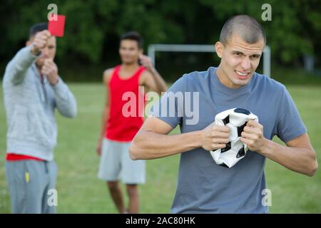 Fußball Schiedsrichter eine rote Karte gegen einen wütenden Spieler Stockfoto