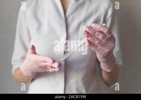Eine behandschuhte Hand mit einem medizinischen Tupfer Stockfoto