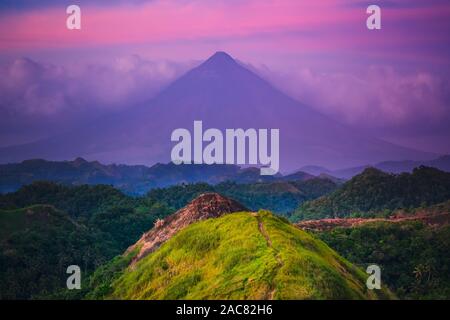 Sonnenuntergang Mayon Vulkan auf der Insel Luzon Philippinen. Wilden Dschungel Bäume und Büsche, Berg und bewölkter Himmel. Panorama Fotografie auf erstaunliche Exotische nationalen Querformat von Klettern Stockfoto