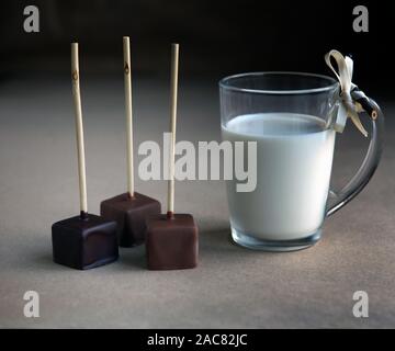 Shocolate Würfel auf einem Stick mit Milch Cup und aromatischem Kakao und Schokolade auf braunem Hintergrund, in der Nähe Stockfoto