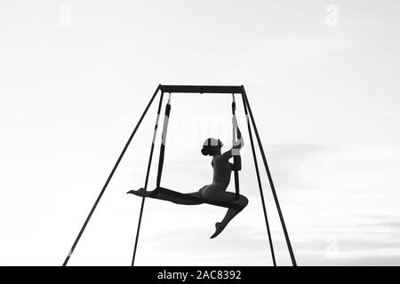 Person, fliegen, tanzen oder Schwerkraft Yoga Posen in einer Hängematte im Freien. Schwarz-weiß Foto. Abstrakte und Konzept weiblichen Sport Foto. Akrobatische Gymnastik dar. Stockfoto
