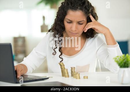 Frau mit Stapeln von Münzen mit einem Laptop Stockfoto