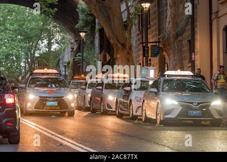 Eine Linie von Taxis warten mit ihrem Licht auf außerhalb eines Gebäudes in Sydney am frühen Abend Stockfoto