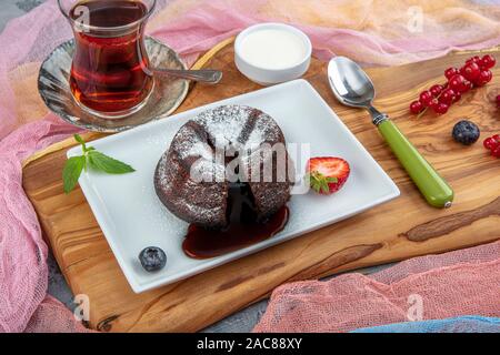 Schokolade souffle mit Schmelzen. Schokolade Fondant lava Kuchen mit Erdbeeren. Stockfoto
