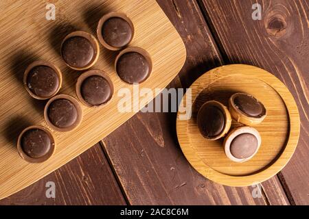 Menge ganz süßen braunen Toffee auf Bambus Schneidbrett auf runden Bambus Untersetzer flatlay auf braunem Holz Stockfoto