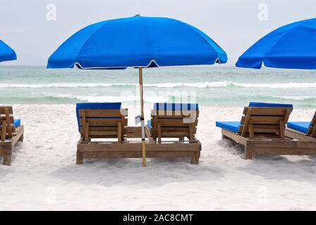 Leere Holzliegen mit blauen Schirme für den Zucker, weißen Sandstrand von einem Strand in Panama City Beach Florida. Stockfoto