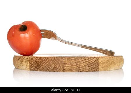 Ein ganzes abgestanden rote Tomate auf Bambus Platte mit Metall- Gabel auf weißem Hintergrund Stockfoto