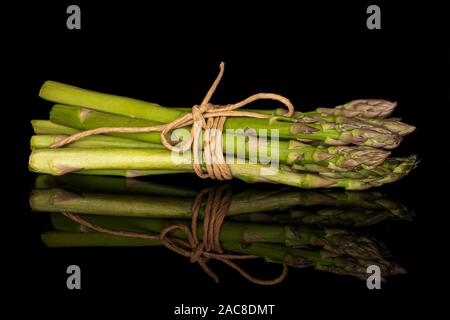 Menge ganz gesunden grünen Spargel mit Stroh Seil auf schwarzem Glas isoliert Stockfoto