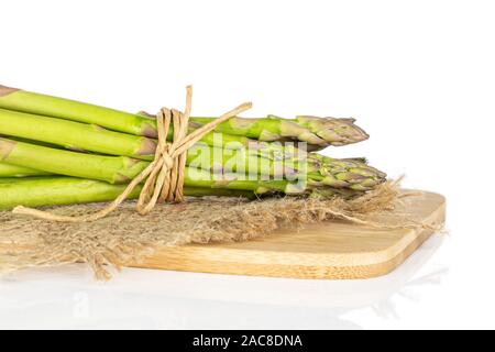 Menge ganz gesunden grünen Spargel auf Bambus Schneidebrett mit Stroh Seil und Jutegewebe auf weißem Hintergrund Stockfoto