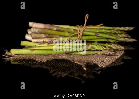 Menge ganze Frische, gesunde grüner Spargel mit Stroh Seil und Jutegewebe auf schwarzem Glas isoliert Stockfoto