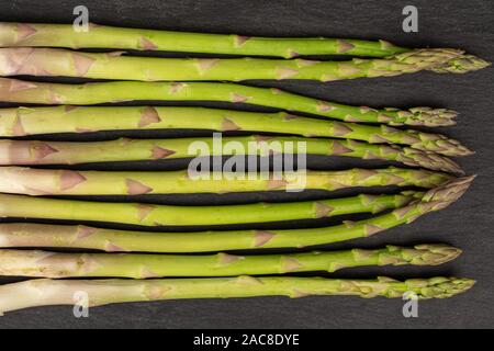 Menge ganz gesunden grünen Spargel flatlay am grauen Stein Stockfoto