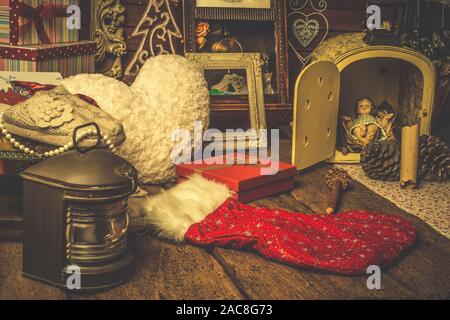 Weihnachten retro Grußkarte. Figurine des Jesus Kindes durch Weihnachten Objekte, Geschenke, vintage Deko umgeben. Stockfoto