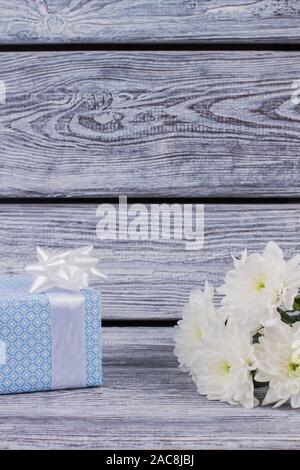Blaue Geschenkbox und weiße Chrysanthemen. Stockfoto