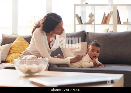 In warmen Tönen Porträt der jungen Afrikaner Mutter interessieren für Cute Baby zu Hause, Kopie Raum Stockfoto