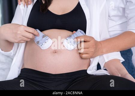 Mann und Bauch der schwangeren Frau mit Baby Socke Stockfoto