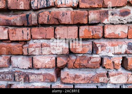 Der Hintergrund ist aus roten Ziegeln mit einem welligen Relief, Risse, Löcher und Gräben gemacht. Baumaterial für die Dekoration und Einrichtung im Stil einer Loft. Stockfoto