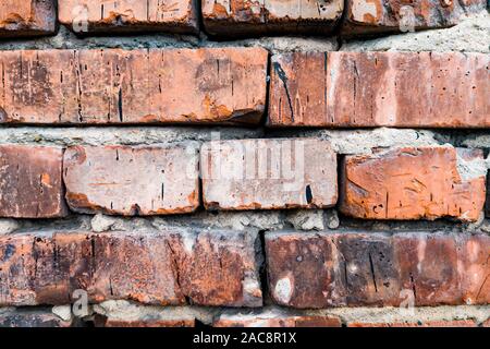 Der Hintergrund ist aus roten Ziegeln mit einem welligen Relief, Risse, Löcher und Gräben gemacht. Baumaterial für die Dekoration und Einrichtung im Stil einer Loft. Stockfoto