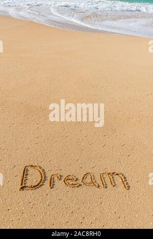 Das Wort Traum in den Sand am Strand geschrieben mit einer Welle in der Waschmaschine Stockfoto