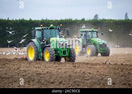 Sheffield, Canterbury, Neuseeland, 30. November 2019: John Deere Traktoren bei der Arbeit in einem Feld, den Boden zu kultivieren bereit für Kartoffeln gepflanzt zu werden Stockfoto