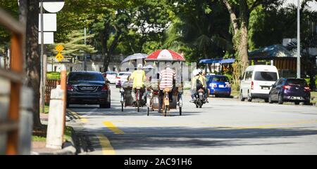 Einige Trishaw Fahrer fahren durch die Straßen von George Town. George Town ist die Hauptstadt der P Stockfoto