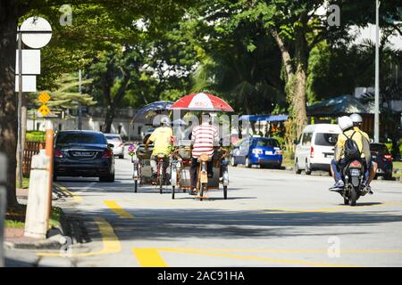 Einige Trishaw Fahrer fahren durch die Straßen von George Town. George Town ist die Hauptstadt der P Stockfoto